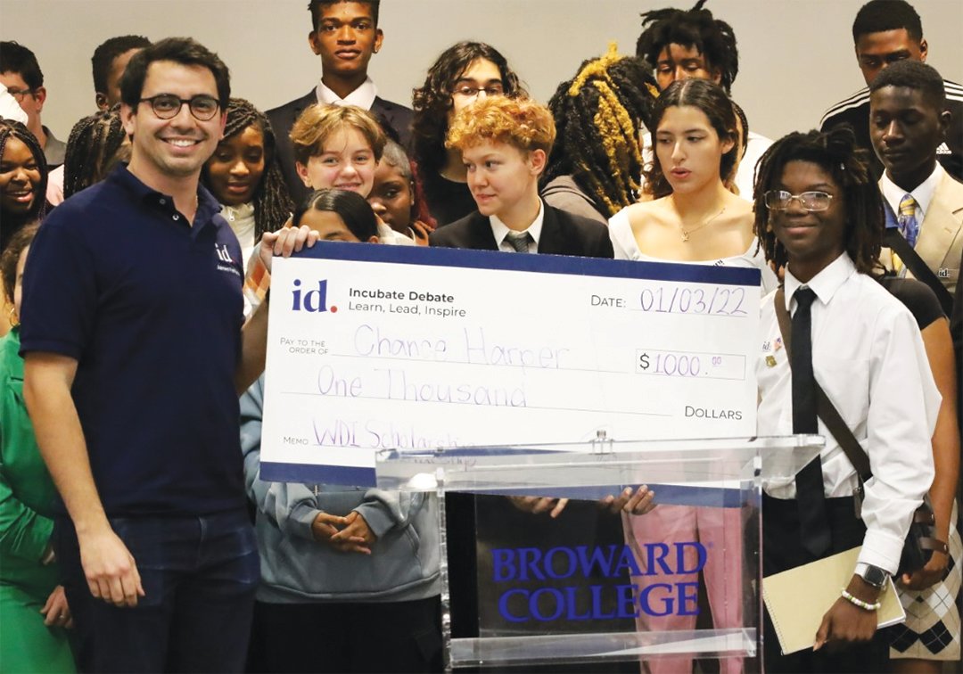 Incubate Debate Founder and Executive Director James T. Fishback (left) presents a college scholarship check to CHS freshman Chance Harper Jan. 3 at the fourth annual Winter Debate Institute at Broward College. Harper was selected as the most improved student over the entire camp, recognizing his hard work and dedication.
